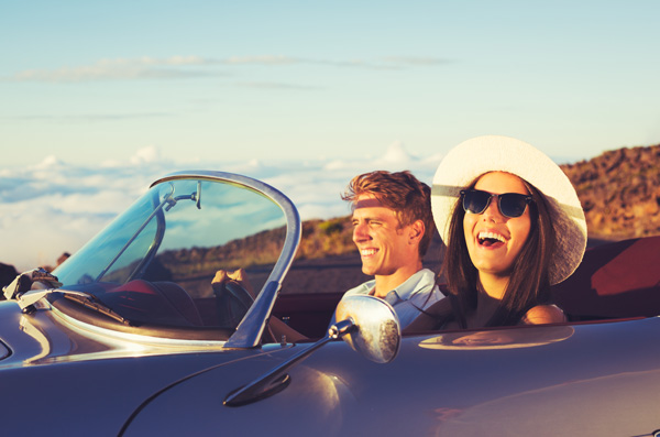 Happy Young Couple in Classic Vintage Sports Car at Sunset